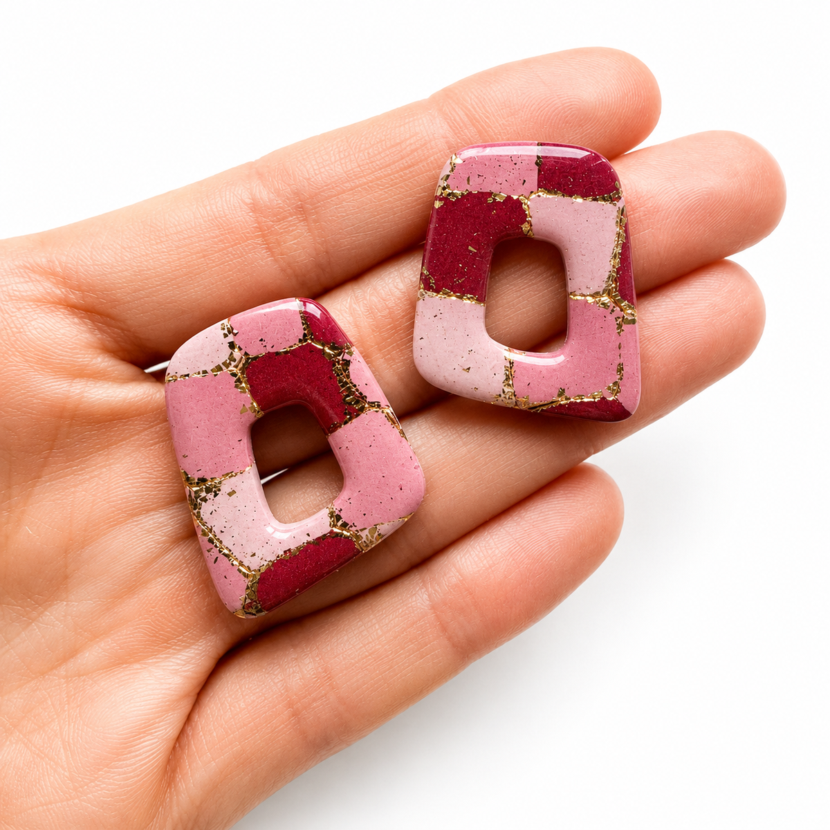Amber cutter, roze met gouden organische polymeerklei oorbellen op hand