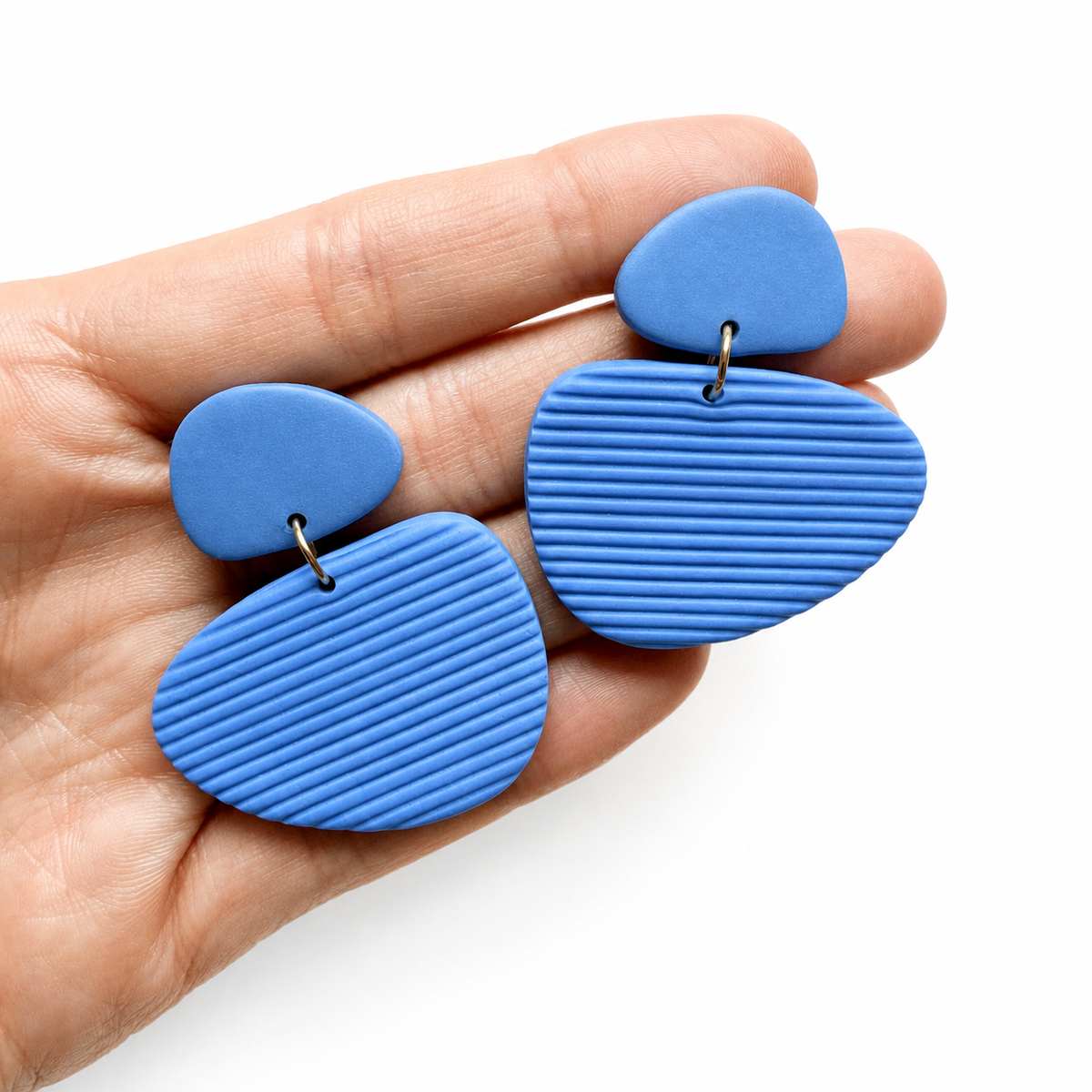 Tess cutter, blauwe grote organische polymeerklei oorbellen op hand