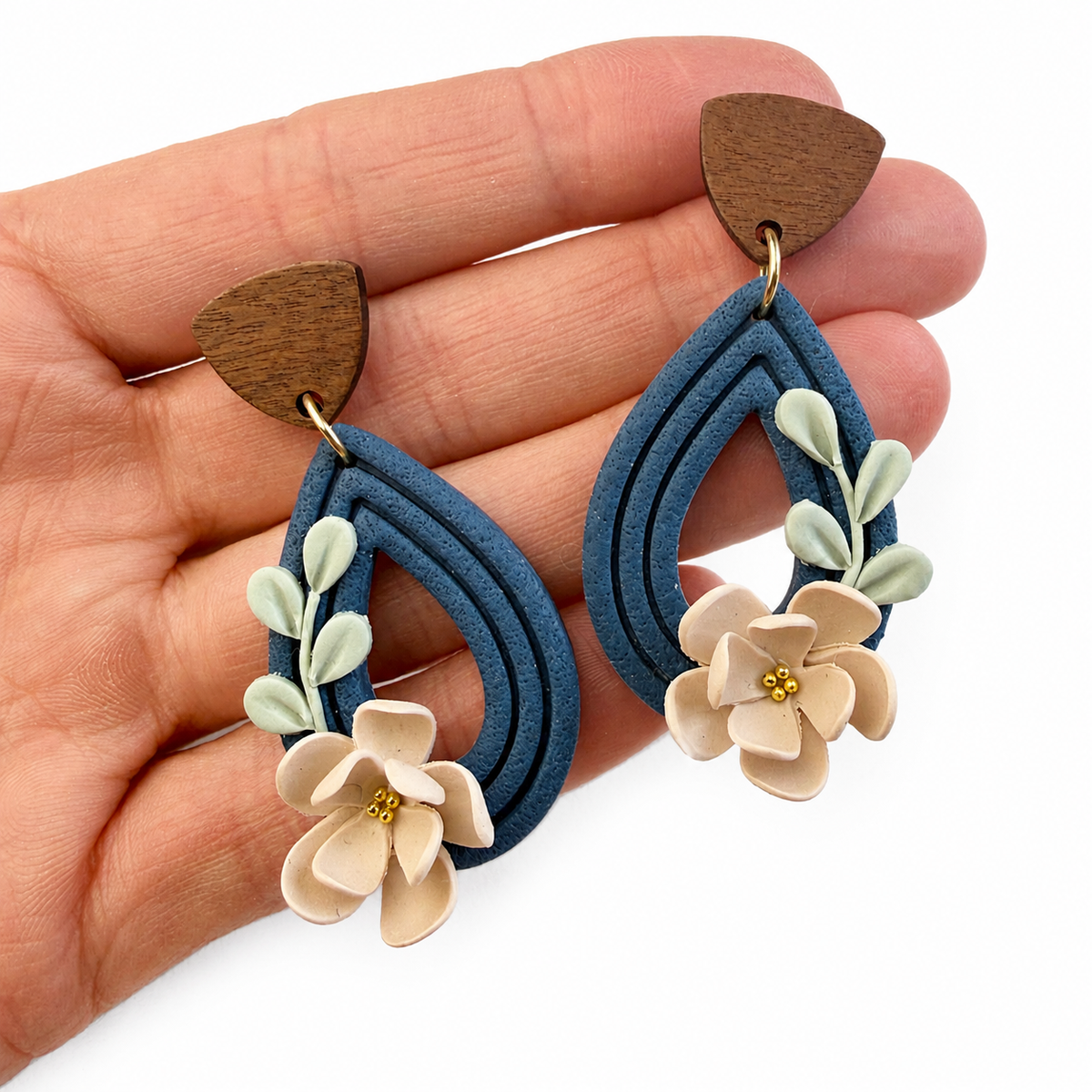 Amelie cutter, blauwe polymeerklei oorbellen met bloemen op hand