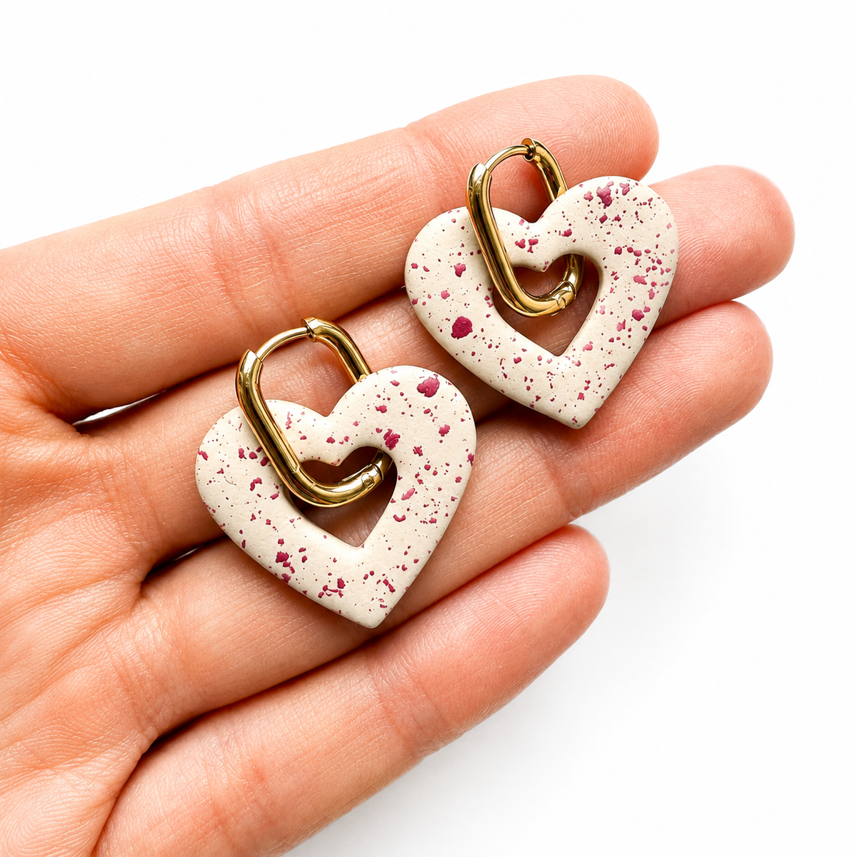 Hartje cutter 2, gestippelde hartjes polymeerklei oorbellen met gouden huggies op hand
