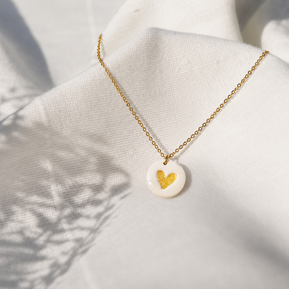 Gouden ketting met witte ronde hanger uit polymeerklei, versierd met gouden hartjes aangebracht met micapoeder.