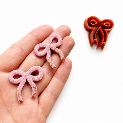 Roze polymeerklei oorbellen strikjes op hand, gemaakt met de strik cutter 2