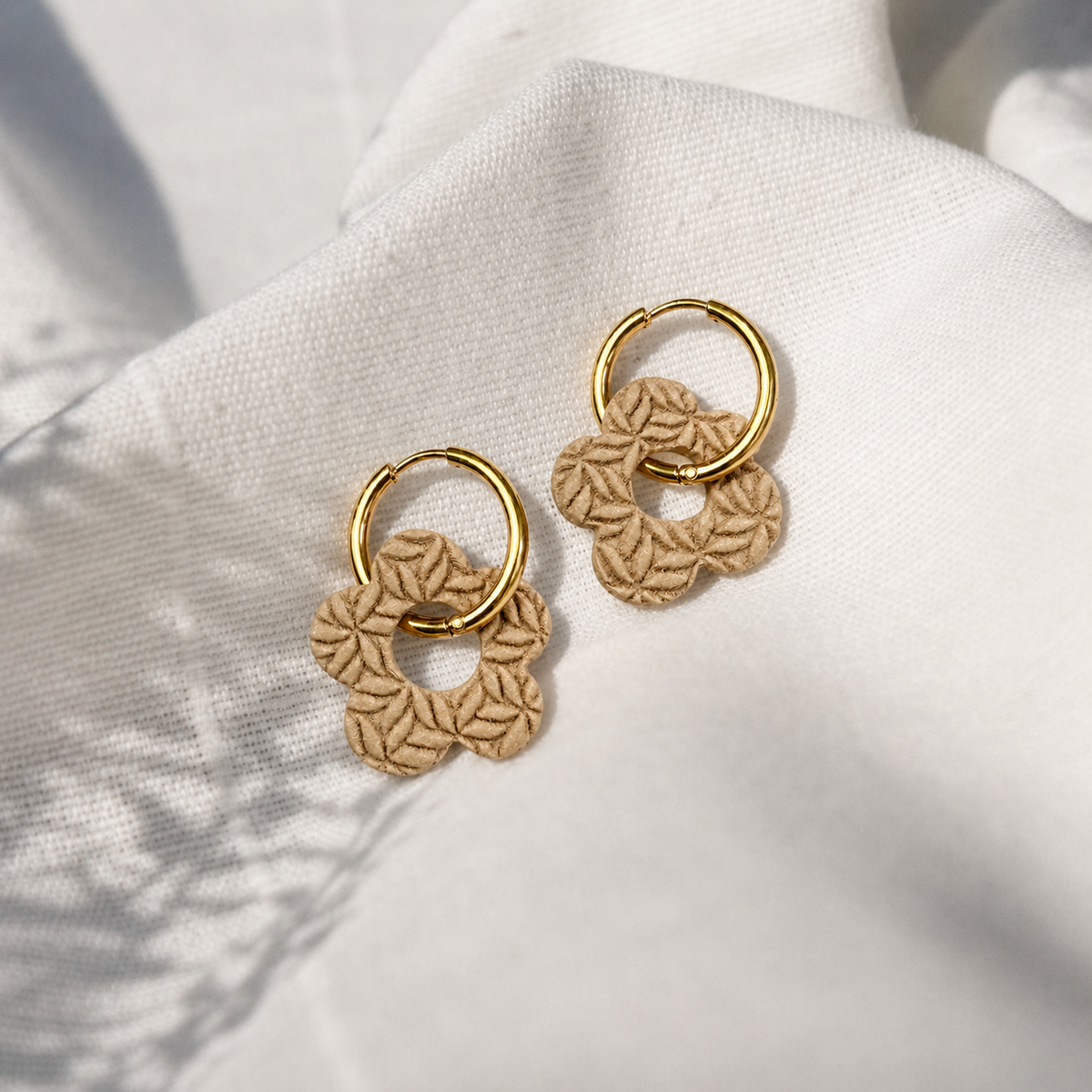 Beige bloemenoorbellen met bloemenreliëf gemaakt met structuurroller bloemen