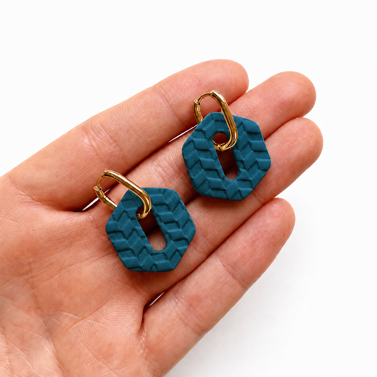 Donker blauwe hexagon oorbellen met visgraatpatroon op hand