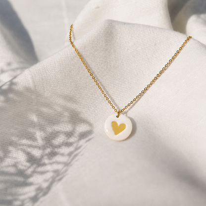 Beige cirkelvormige polymeerklei ketting afgewerkt met de hartje stempel en goud micapoeder
